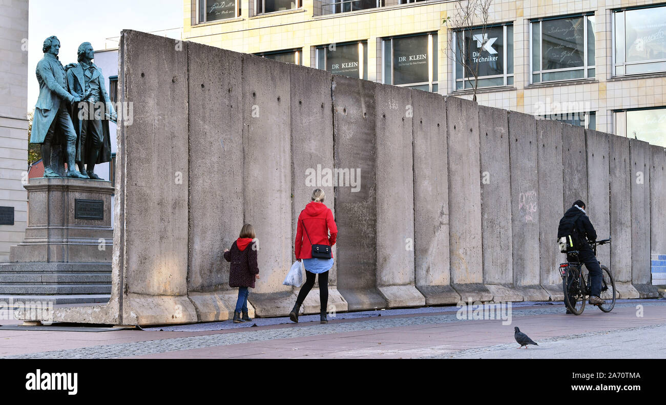 Weimar, Germany. 29th Oct, 2019. Passers-by walk along the wall  installation "Horizons" in memory of the fall of the Berlin Wall in 1989 in  front of the Goethe Schiller Monument and the