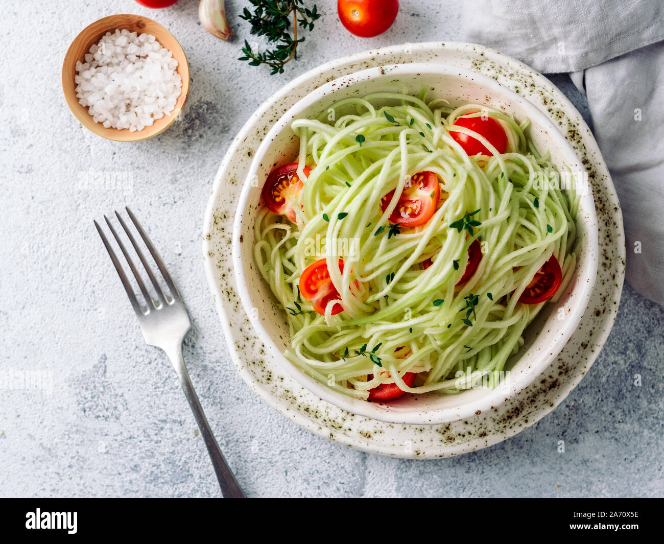 Zucchini noodles salad with cherry tomatoes. Vegetable noodles - green zoodles or courgette spaghetti salad ready-to-eat. Clean eating, raw vegetarian food concept. Copy space. Top view or flat lay. Stock Photo