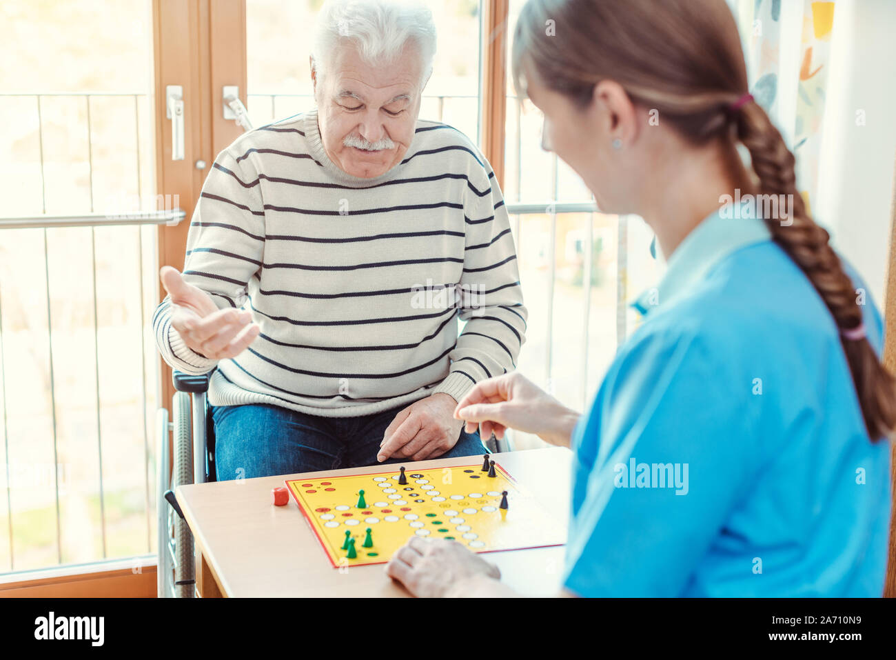 Nurse and senior in retirement home playing a board game Stock Photo