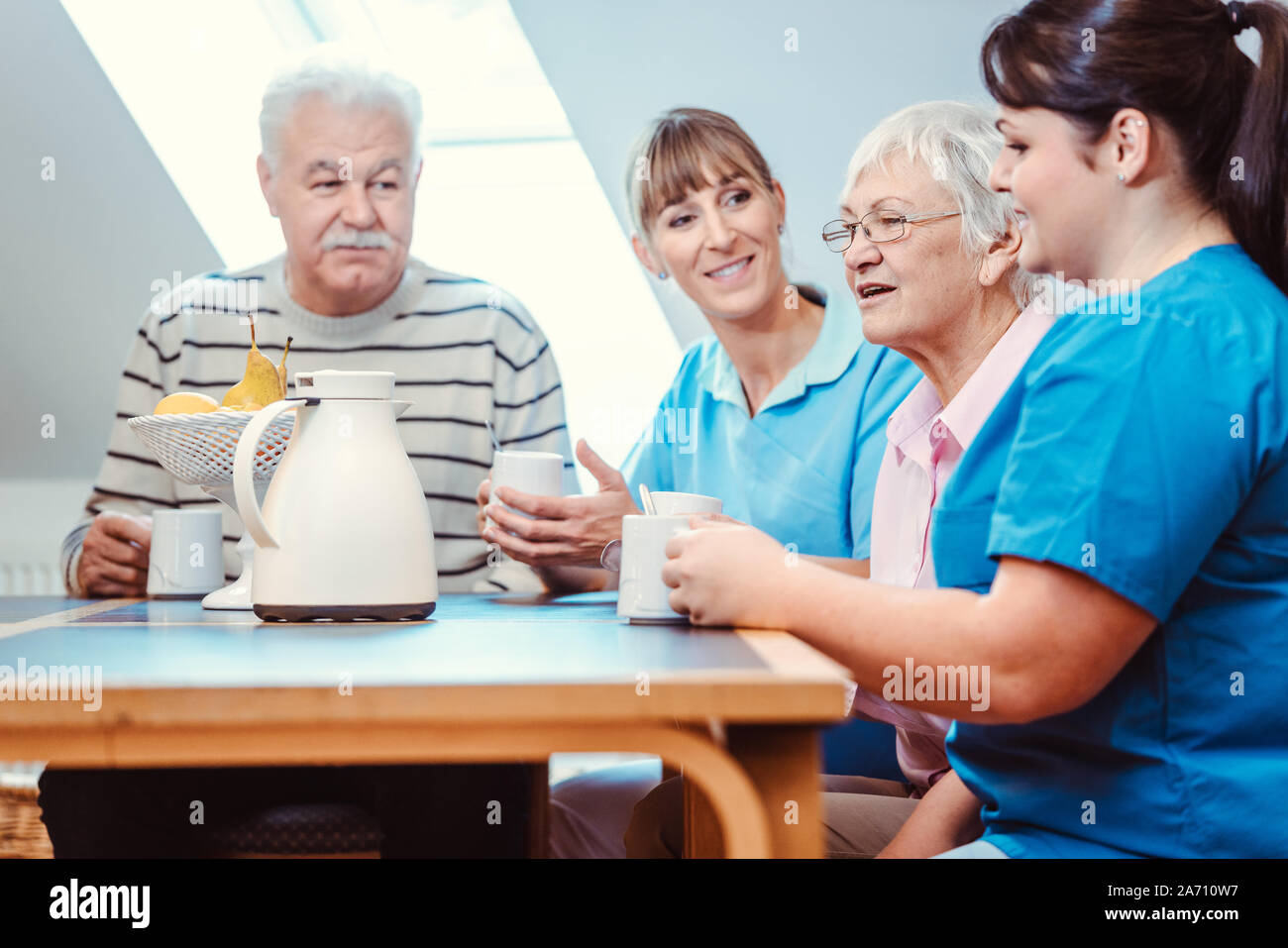 Seniors and caregivers having coffee time in the nursing home Stock Photo
