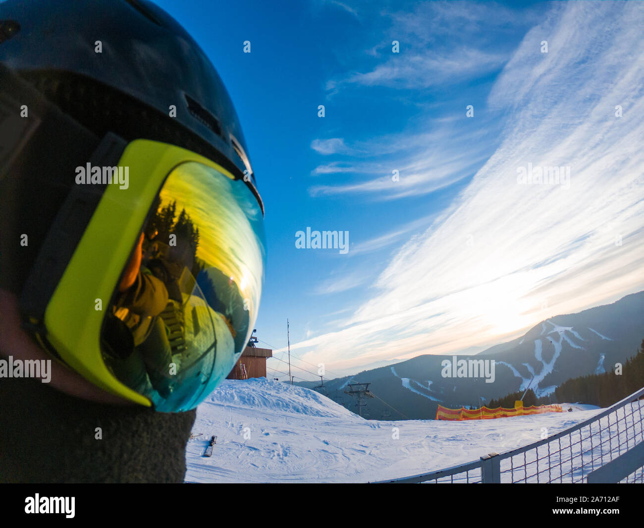 man in ski mask close up. reflection. snowed mountains on sunset Stock Photo