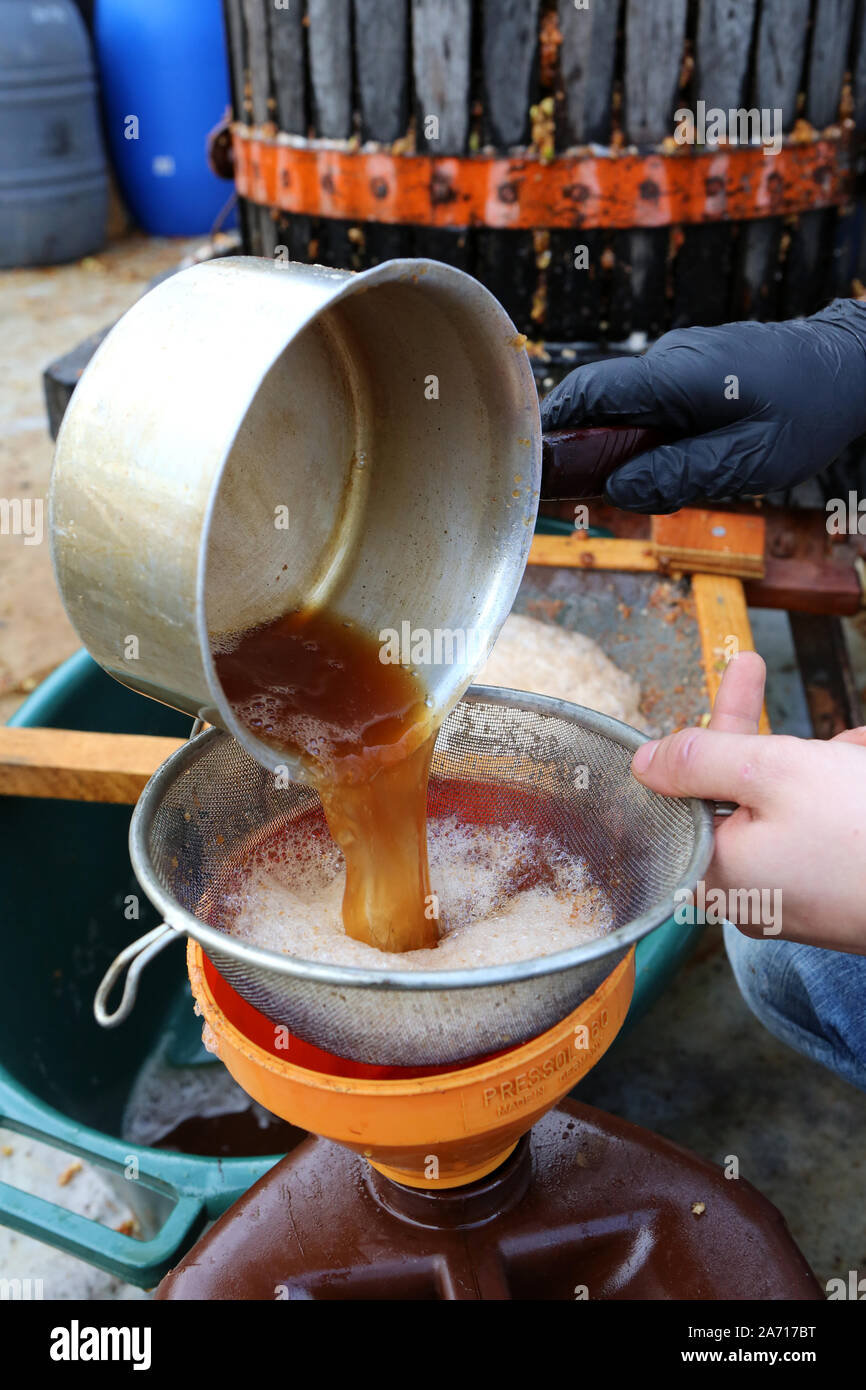 Fabrication de jus de pomme. Verser le jus de pomme dans un tamis. Haute-Savoie. France. Stock Photo
