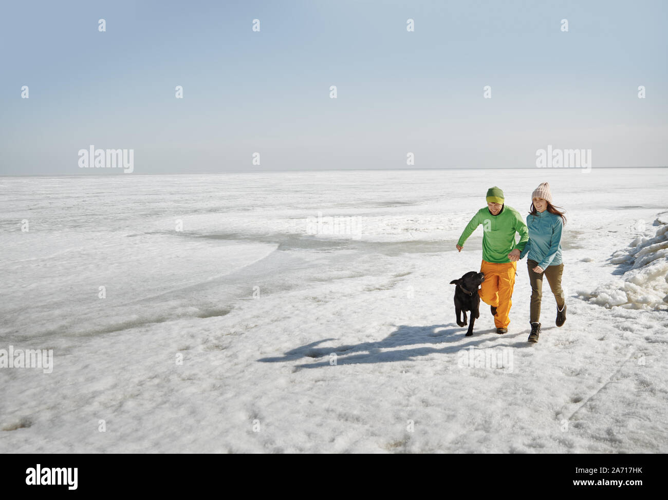 Young adult couple outdoors with dog having fun in winter landscape Stock Photo