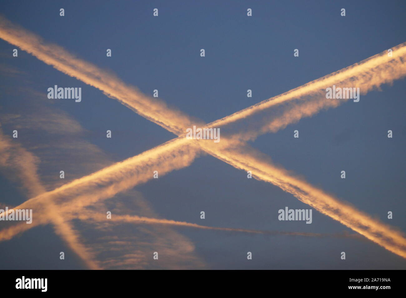 Contrails of a plane in the sky in form of a x Stock Photo