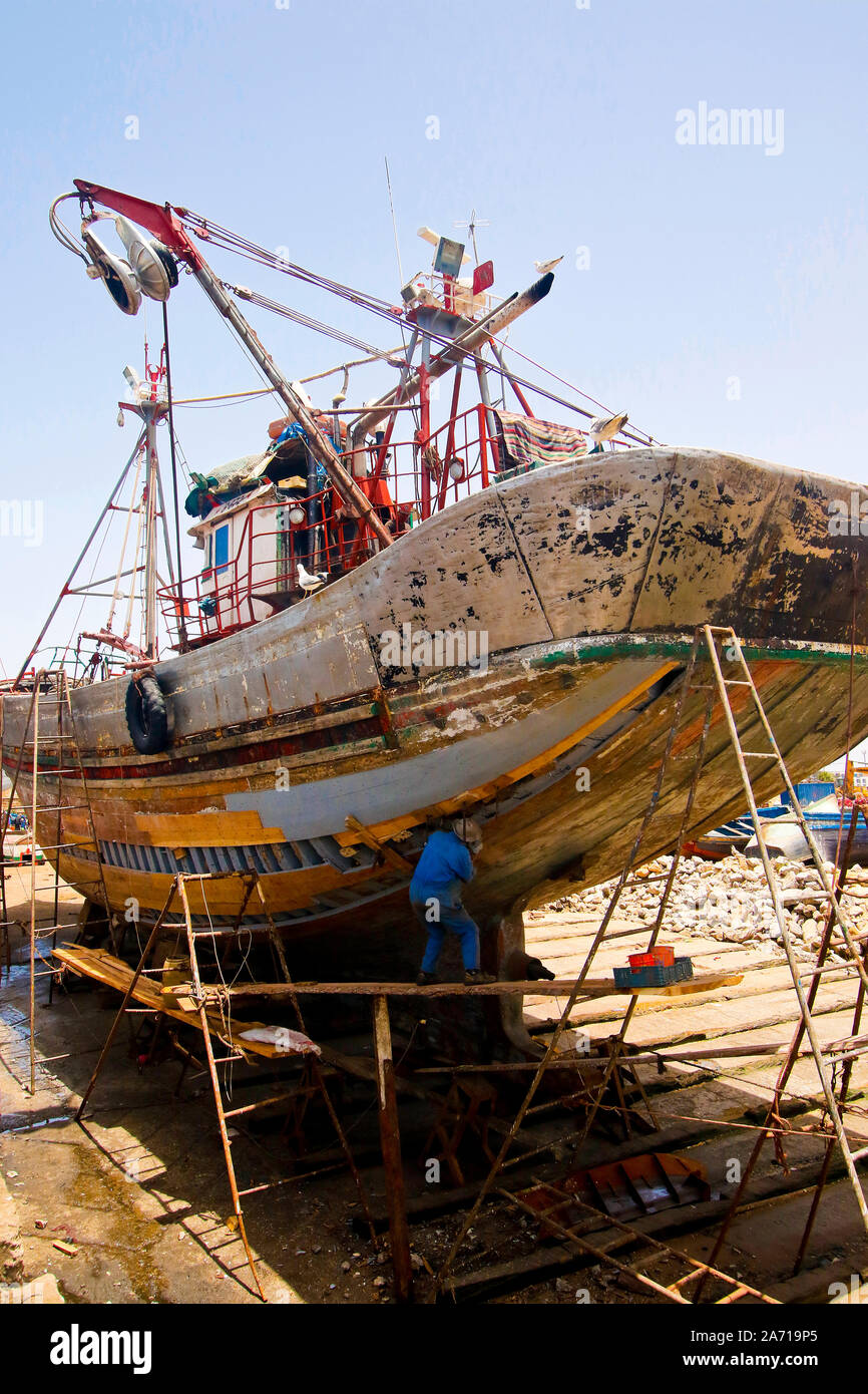 Worker repairing a ship in Essaouira harbour. Morocco Stock Photo