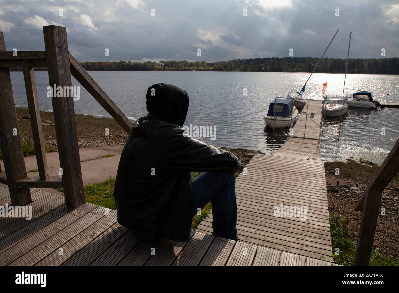 Conceptual image of a lonely man sitting on a riverside and looking on ...