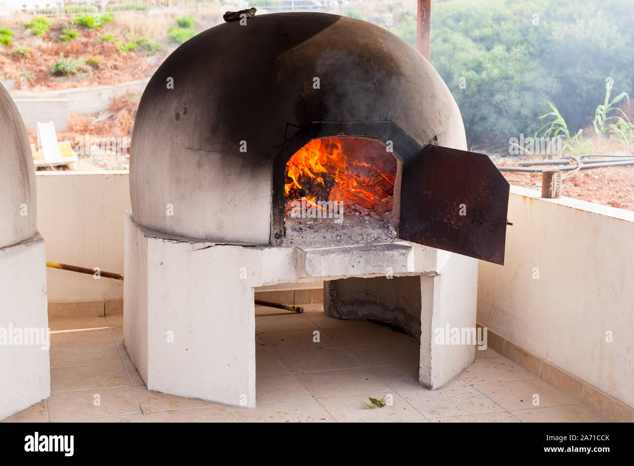 Traditional outdoor Greek and Cyprus kleftiko oven with burning fire inside Stock Photo