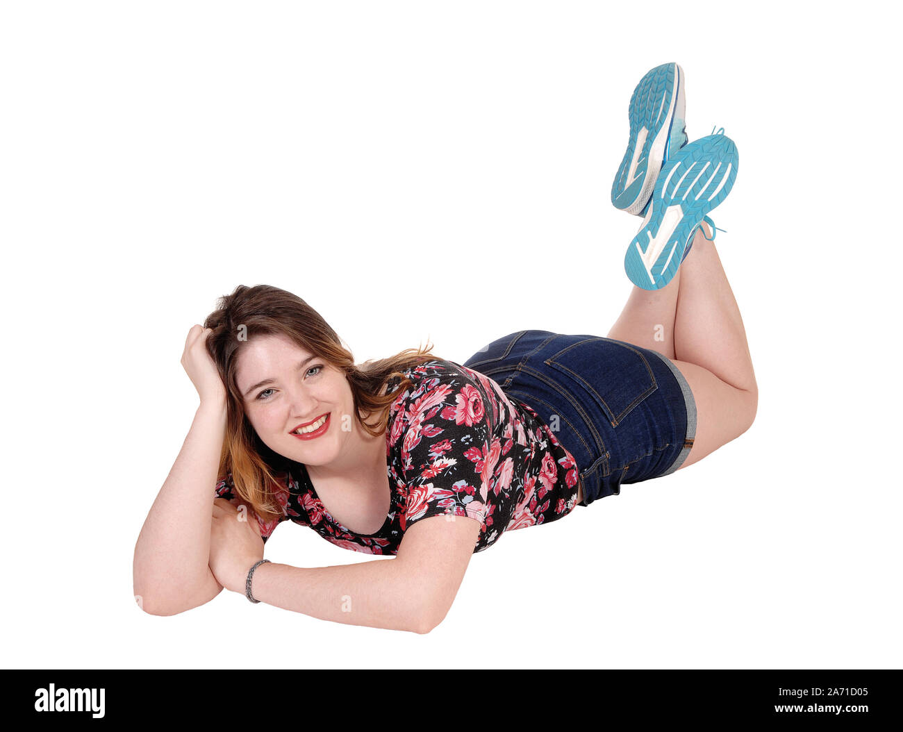 A young beautiful woman lying on her stomach on the floor, looking into the camera, isolated for white background Stock Photo