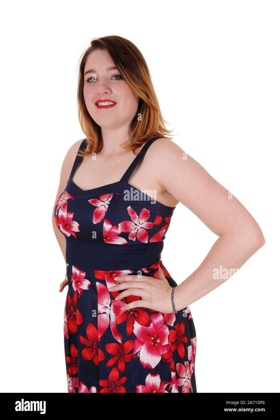 A beautiful young woman standing in a colorful printed dress  with her hands on her hips, isolated for white background Stock Photo