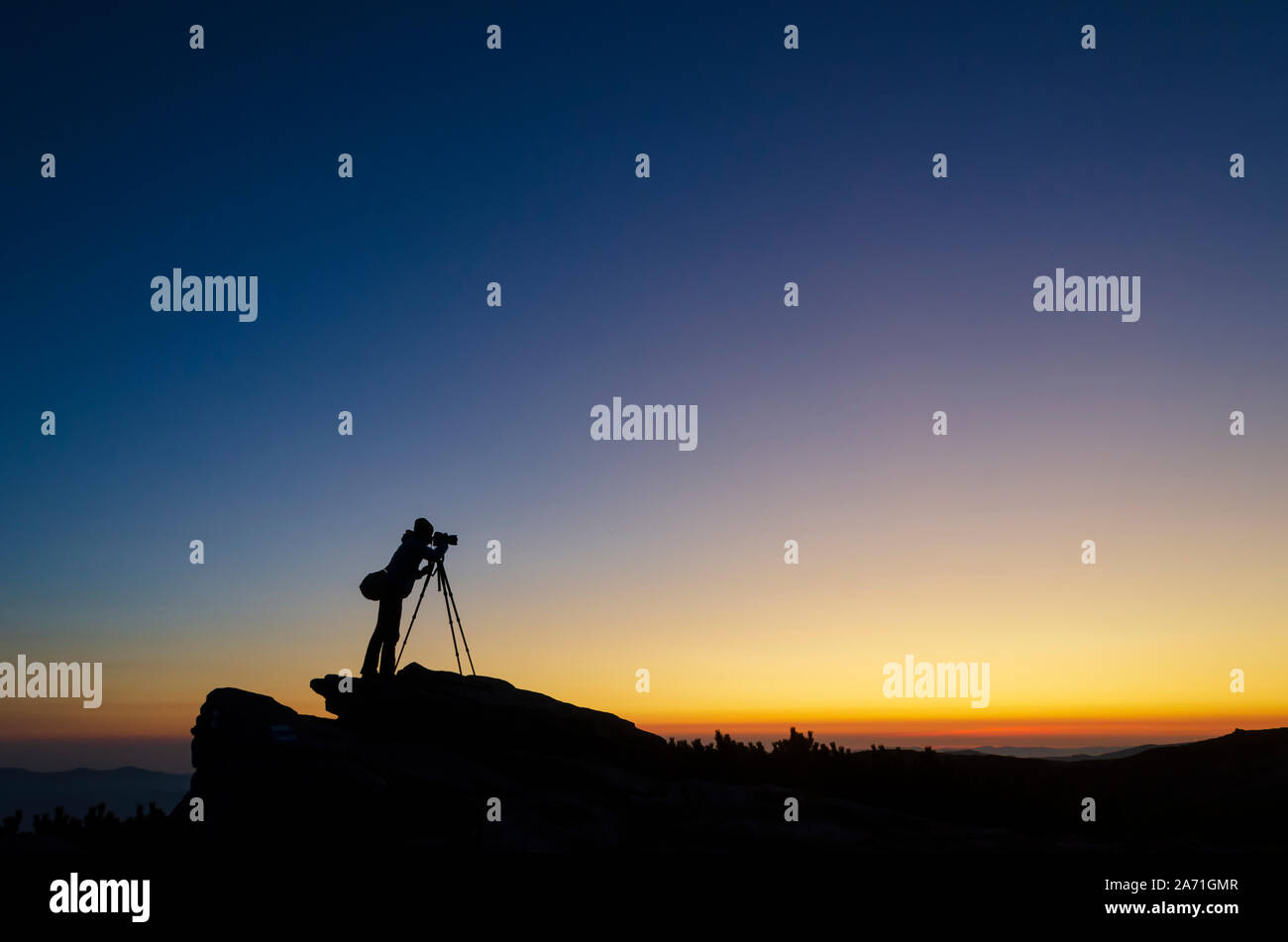 Silhouette of a photographer with a tripod taking photo of a sunset ...
