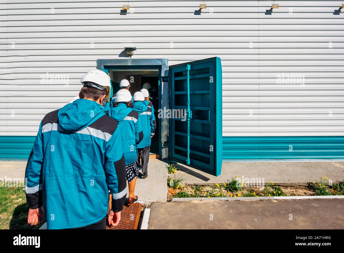 Factory workers enter to armored door of bomb shelter. Stock Photo