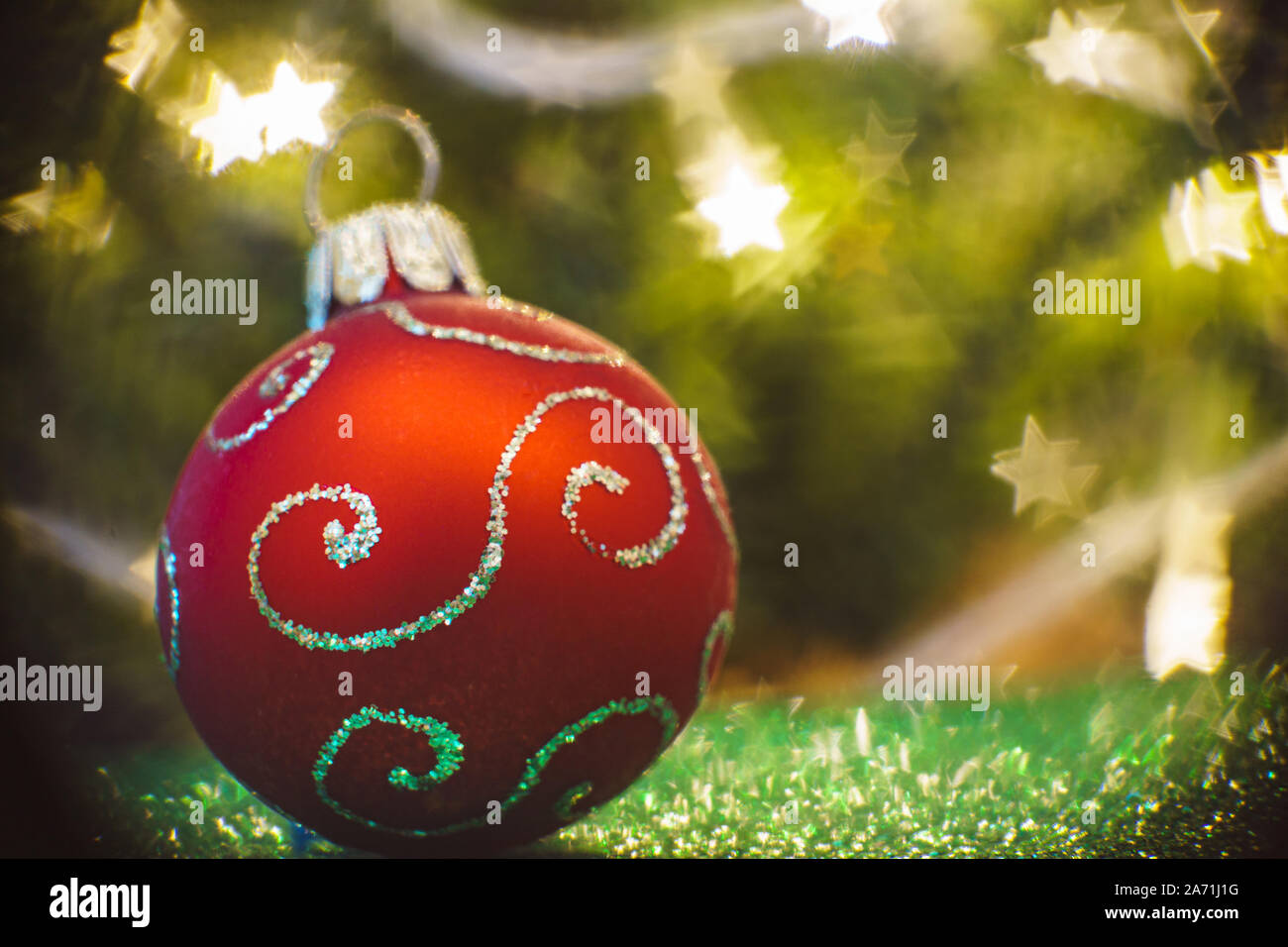 Red Christmas ornament ball with golden design and blurry star shaped lights background Stock Photo