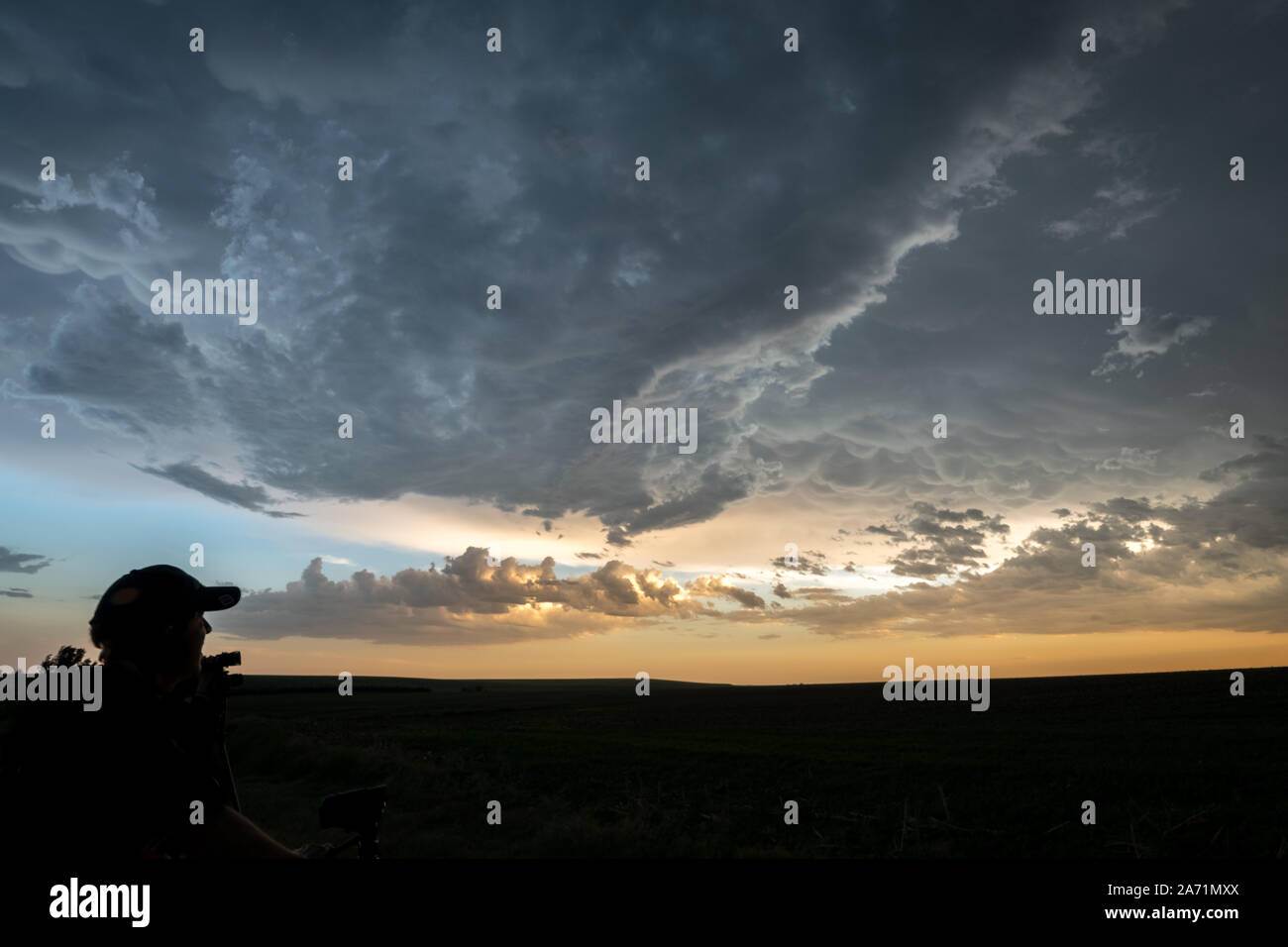 Silhouette of a storm chaser watching a severe thunderstorm over the Great Plains at sunset Stock Photo