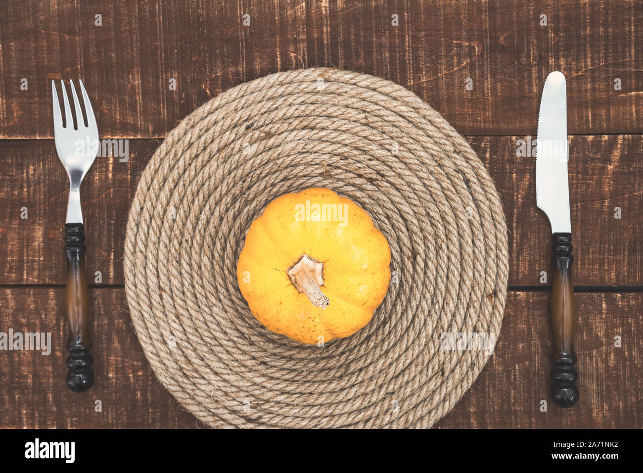 Thanksgiving Day or Halloween place setting with mini pumpkin and cutlery on rustic wooden table, top view with copy space. Stock Photo