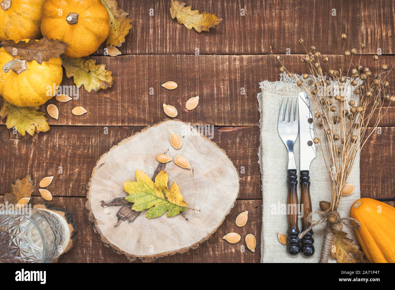 Rustic table setting for Thanksgiving diner with autumn leaves, acorns and pumpkins for decoration. Top view with copy space. Stock Photo