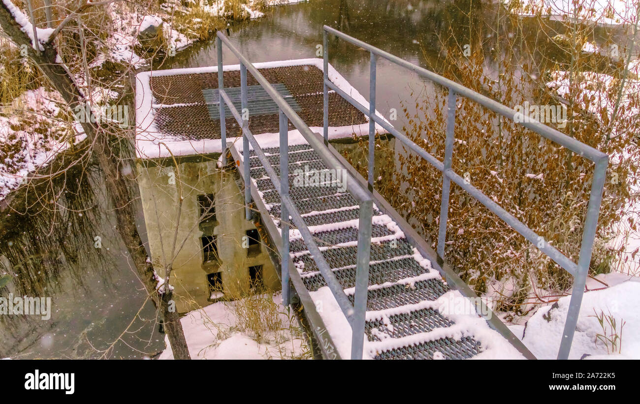 Panorama frame Platform above the man made drain area of a small lake in the snow Stock Photo