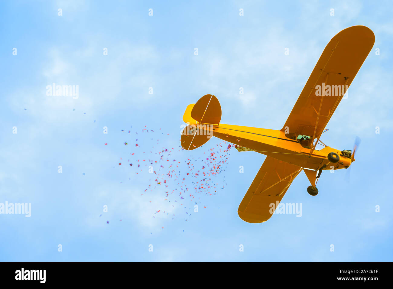 A small yellow bi-plane dropping candy at a local Halloween event Stock Photo