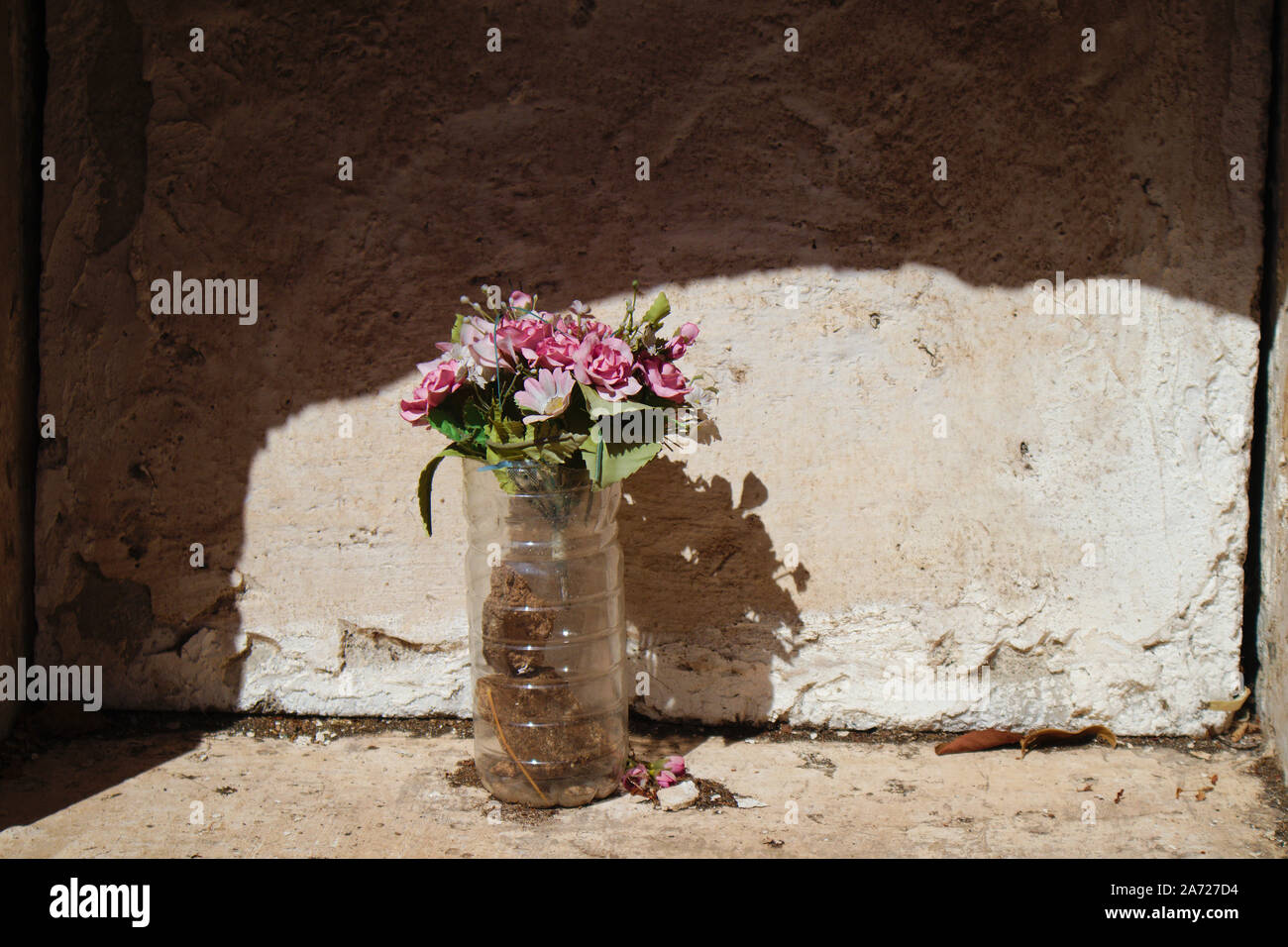 Niche with a simple bouquet of artificial flowers covered in dust in a