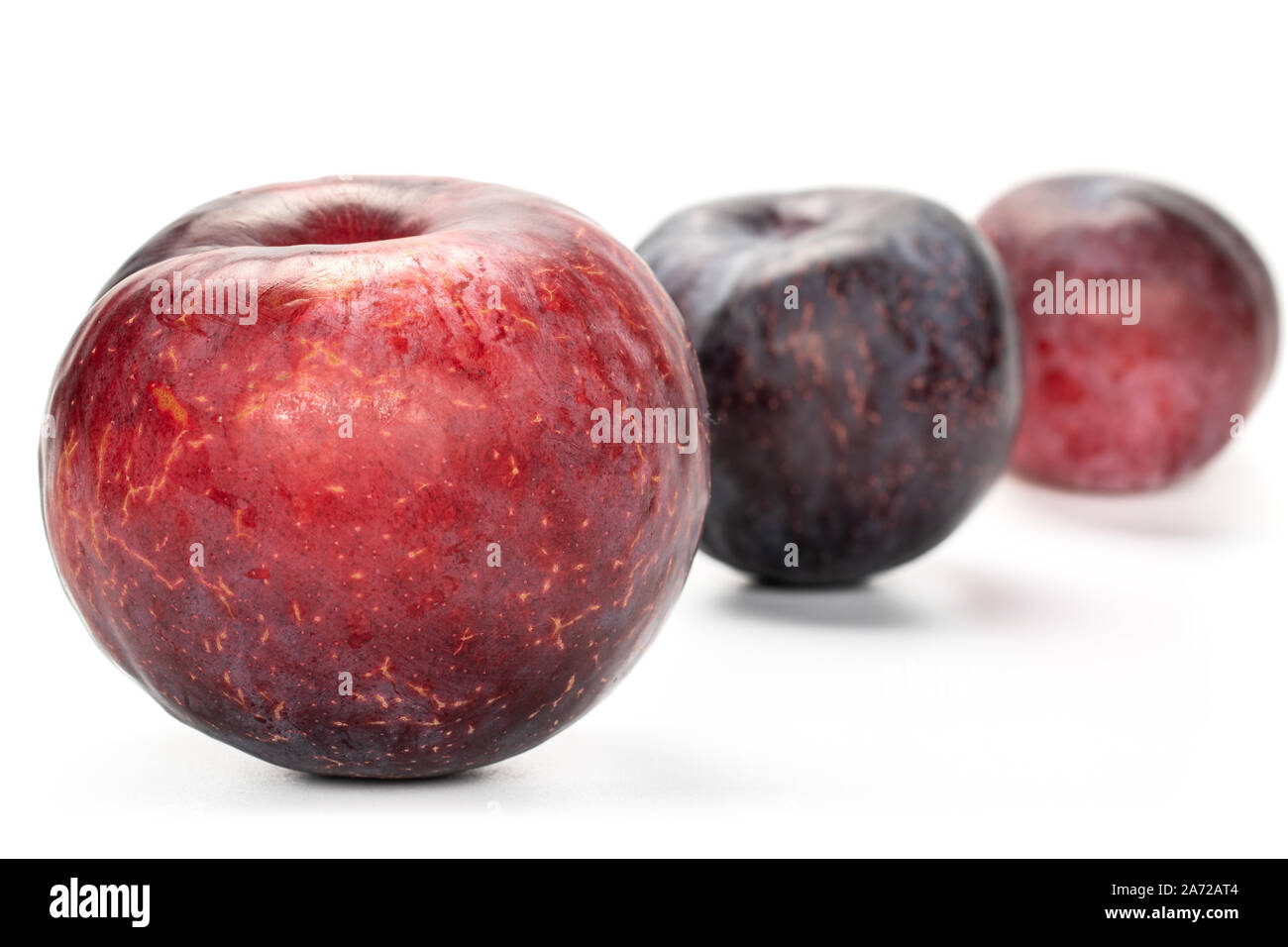 Group of three whole fresh red plum front focus isolated on white ...