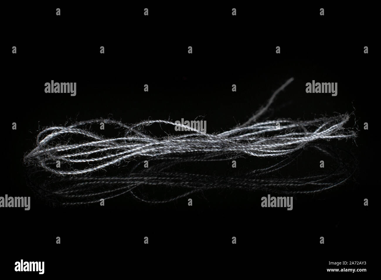 One whole haberdashery item grey thread isolated on black glass Stock Photo