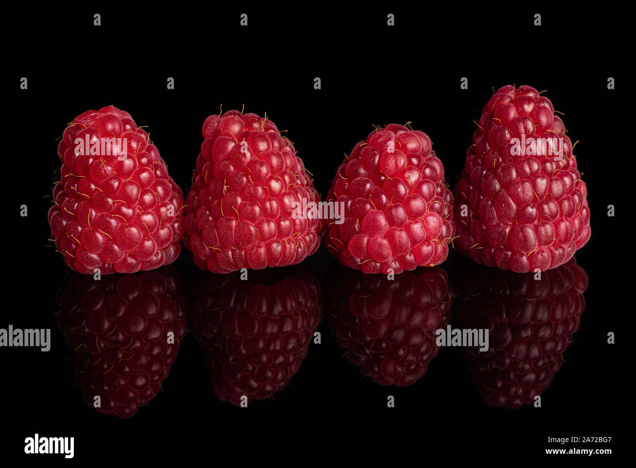 4 Raspberries Group of four whole fresh red raspberry isolated on black glass Stock ...