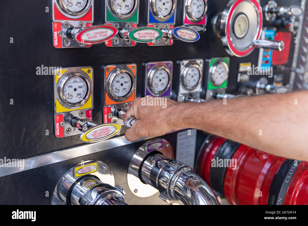 Fireman's hand pulling valve on a fire engine pump panel Stock Photo