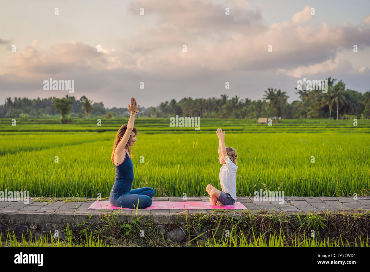 Boy and his yoga teacher doing yoga in a rice field Stock Photo - Alamy