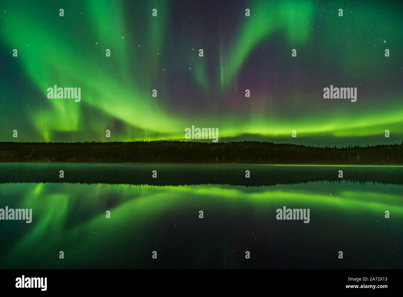 Reflections of the Northern Lights in the calm and misty waters of Madeline Lake on the Ingraham Trail near Yellowknife, NWT on Sept 7, 2019. This is Stock Photo