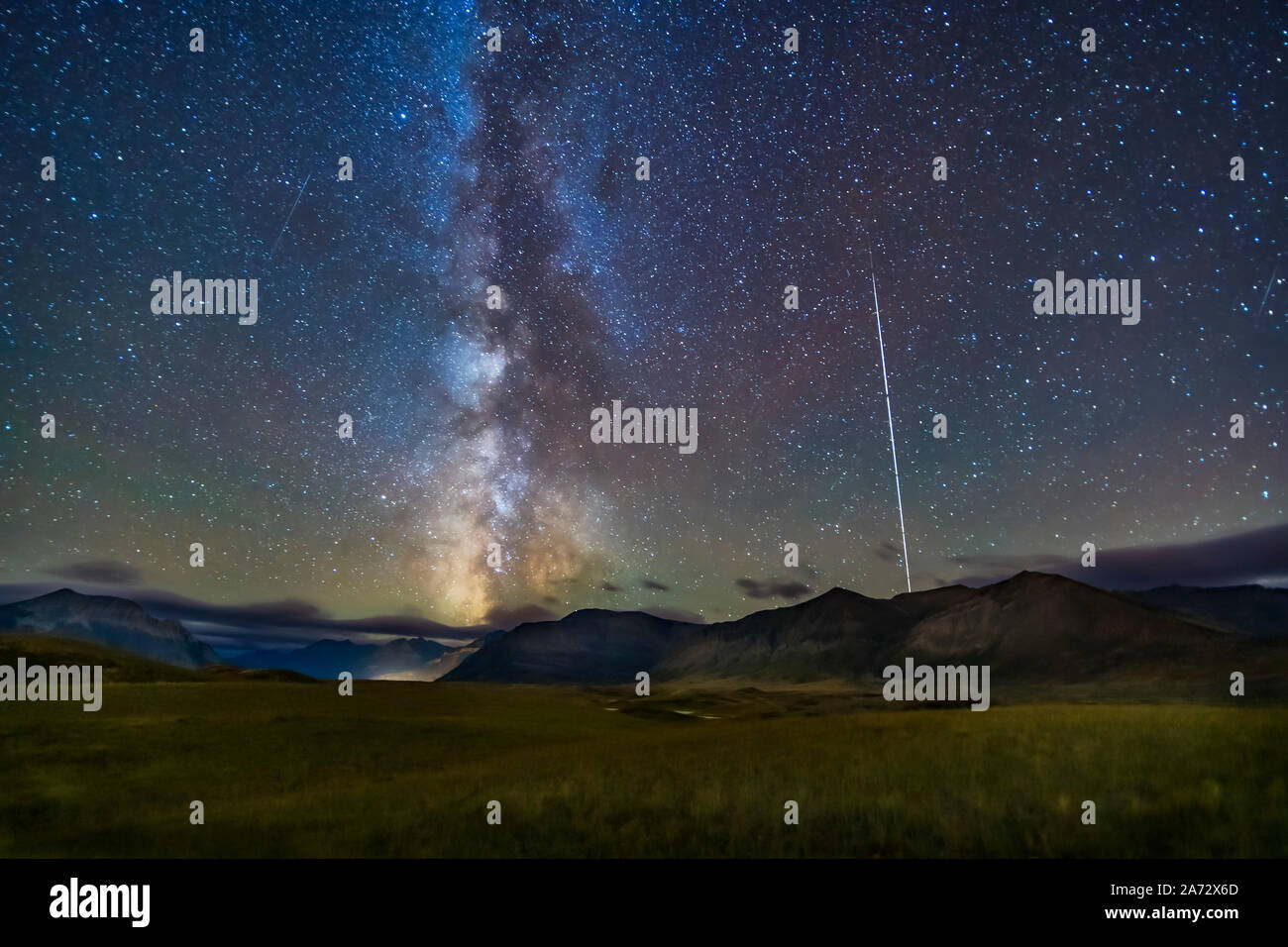 The northern summer Milky Way setting over the mountains of Waterton Lakes National Park, Alberta, Canada, with the Space Station rising at right, the Stock Photo