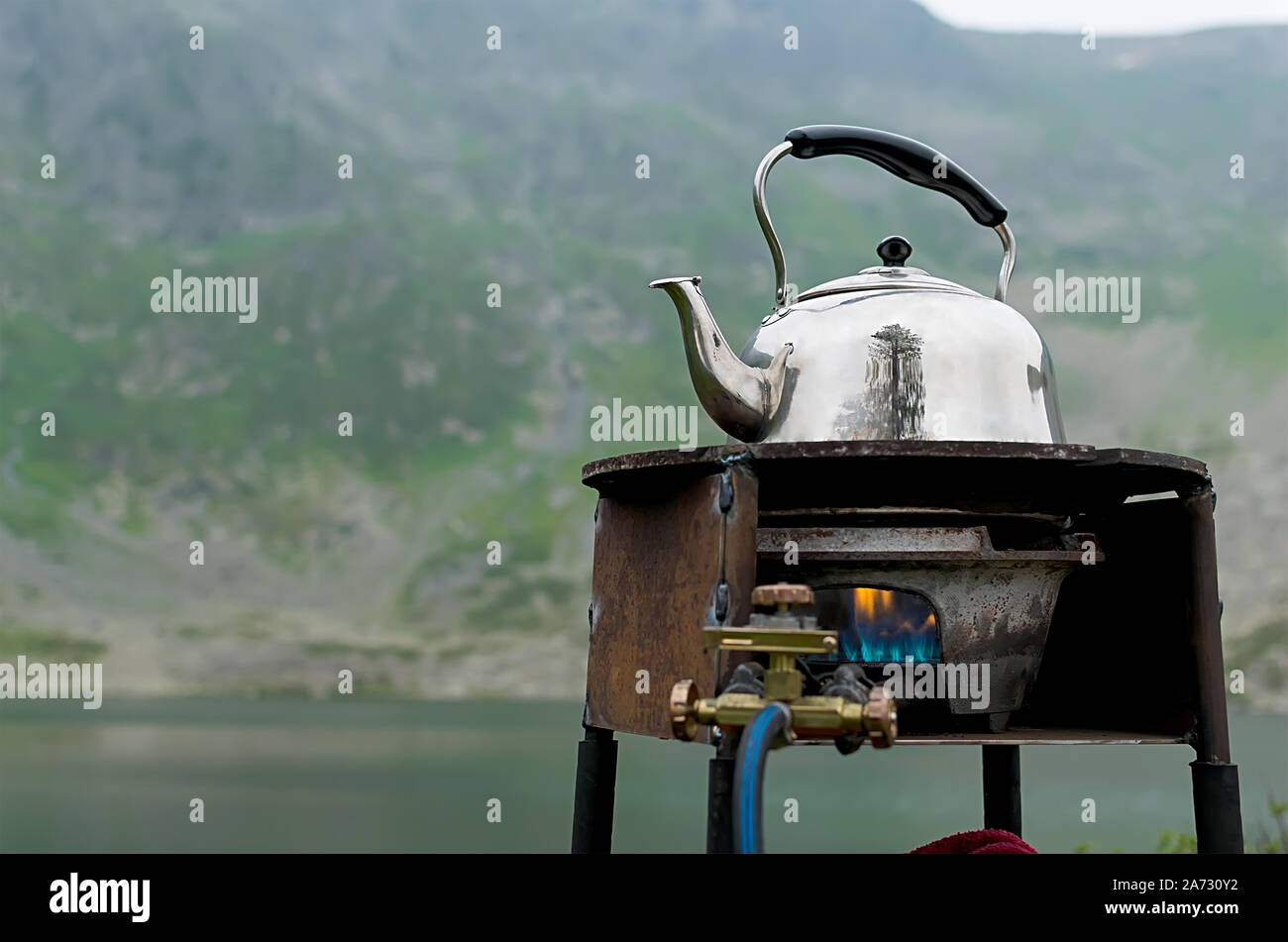 tourism, an old kettle is heated on a rusty gas burner Stock Photo