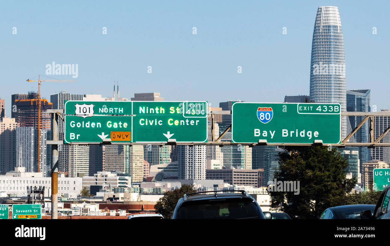 Freeway signage providing direction and information about the upcoming junction; San Francisco downtown skyline visible in the background Stock Photo