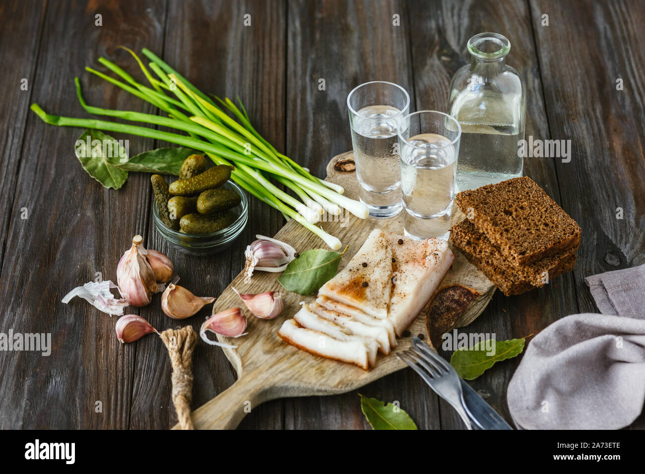 Vodka with lard and green onion on wooden background. Alcohol pure