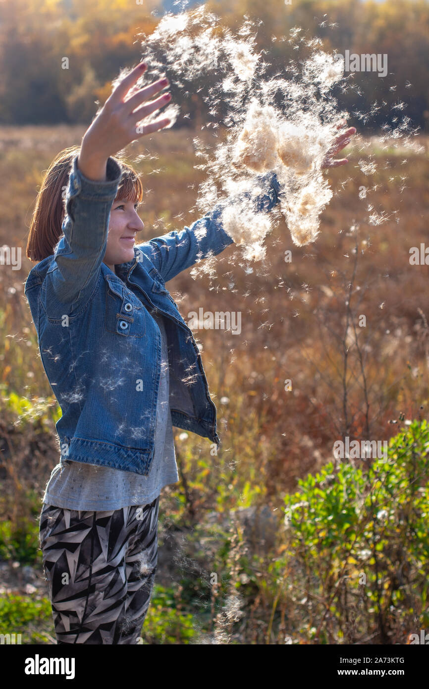 Bulrush Fluff Girl throws fluff from cattail up in the sunshine on a fall day. Autumn ...
