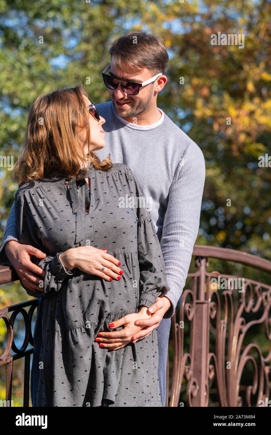 Happy Pregnant Young Woman With Her Husband Standing Together In A Close Embrace Cradling Her Baby Bump In Their Hands Stock Photo Alamy