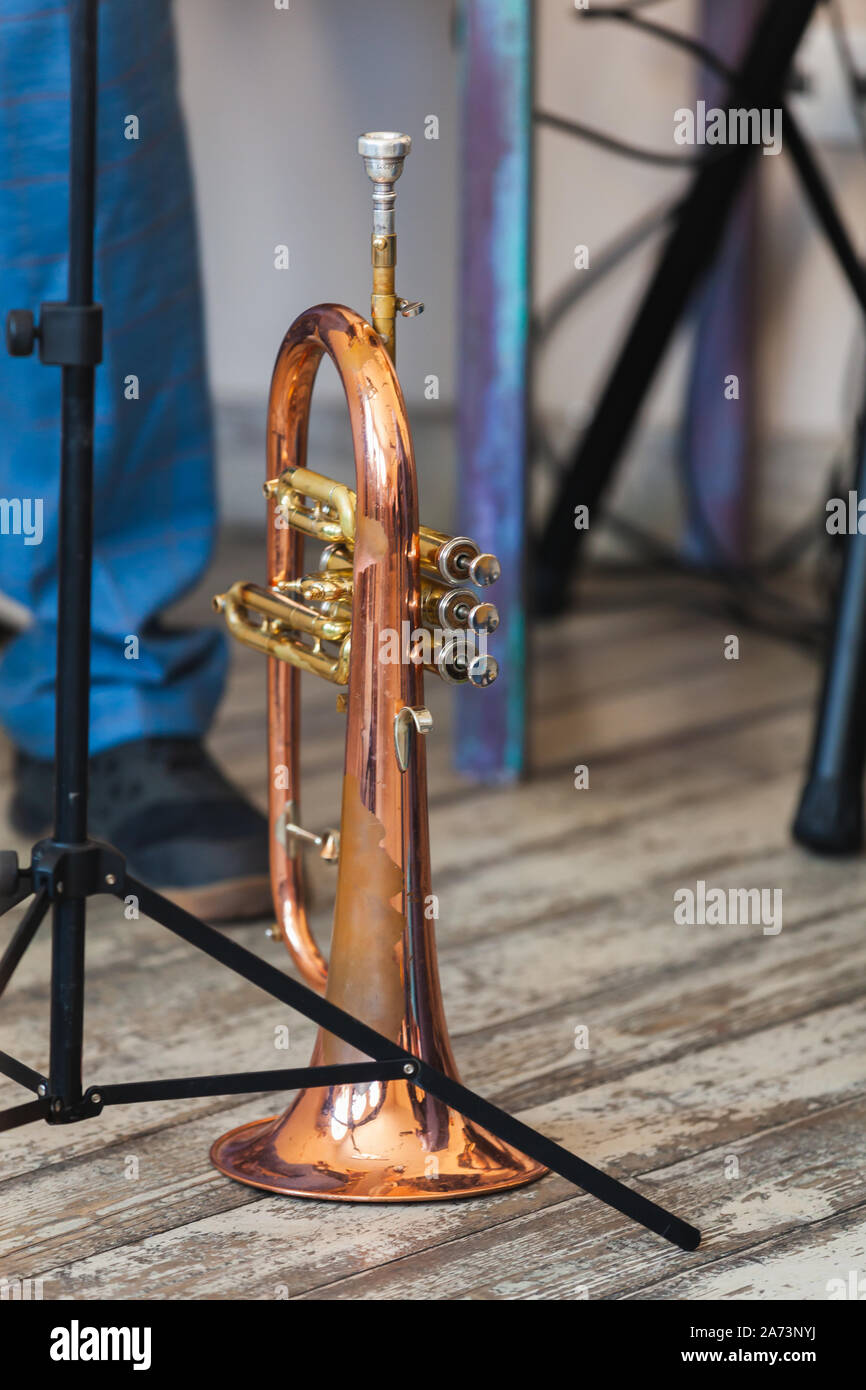 Vintage trumpet stands on grungy wooden floor. It is a brass