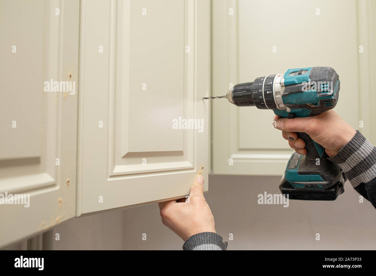 Man using electronic drill to install a cabinet Stock Photo