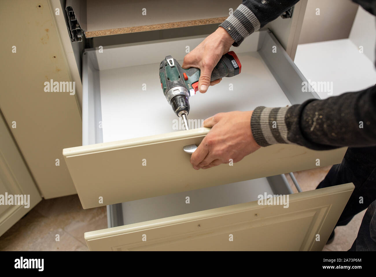 Man using electronic drill to install a cabinet Stock Photo