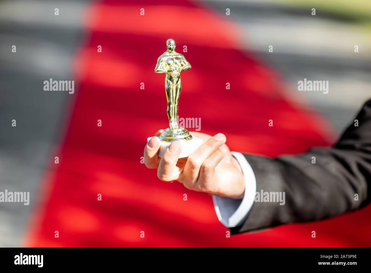 Man holding famous film award statue on the red carpet background, close-up view Stock Photo