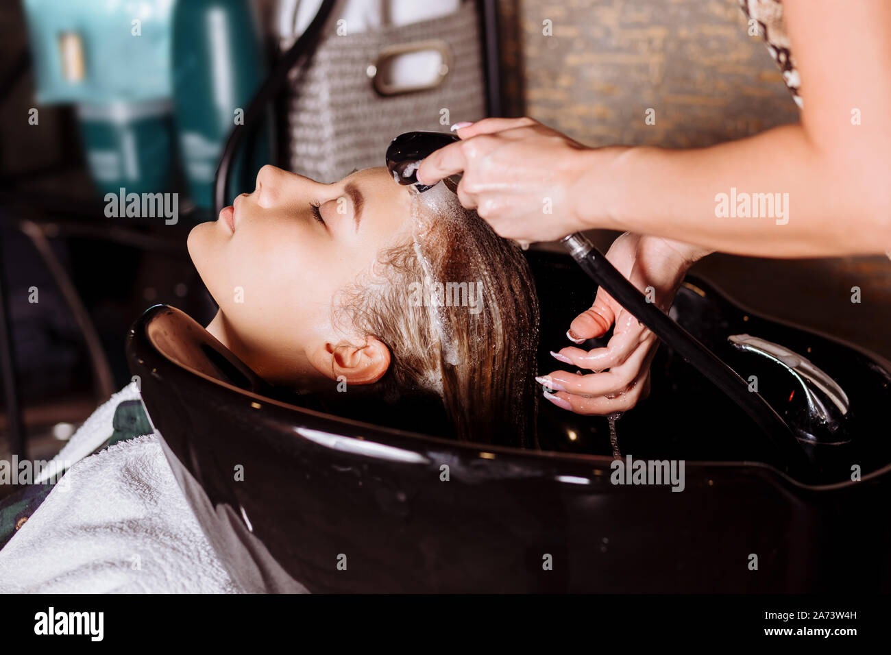Closeup of woman hairdresser washing hair clients in hair salon Stock Photo