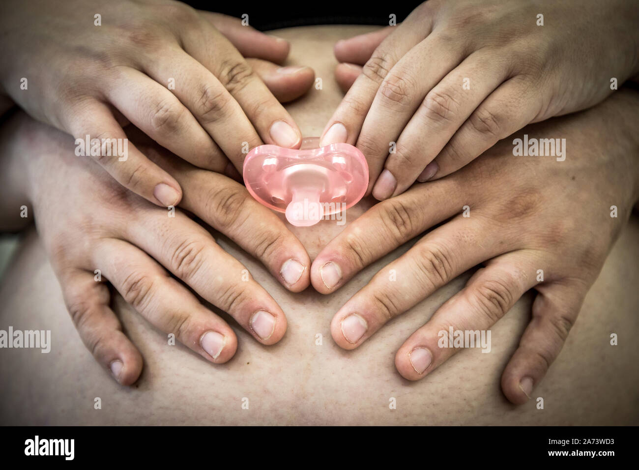 Mom and Dad hands holding pink pacifier, on Pregnant woman belly Stock  Photo - Alamy