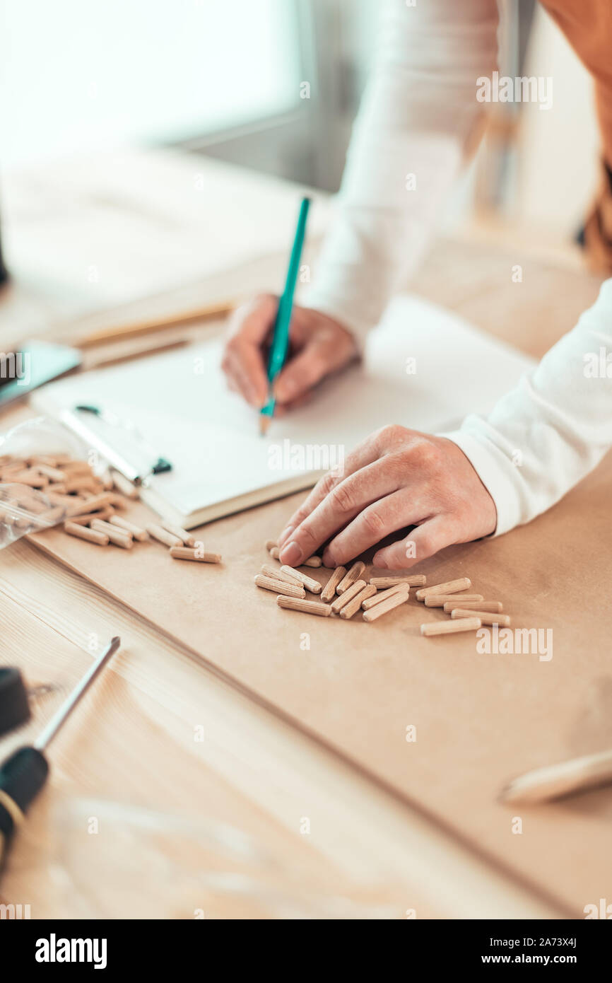 Female carpenter working with wooden dowels in carpentry woodwork workshop, selective focus Stock Photo