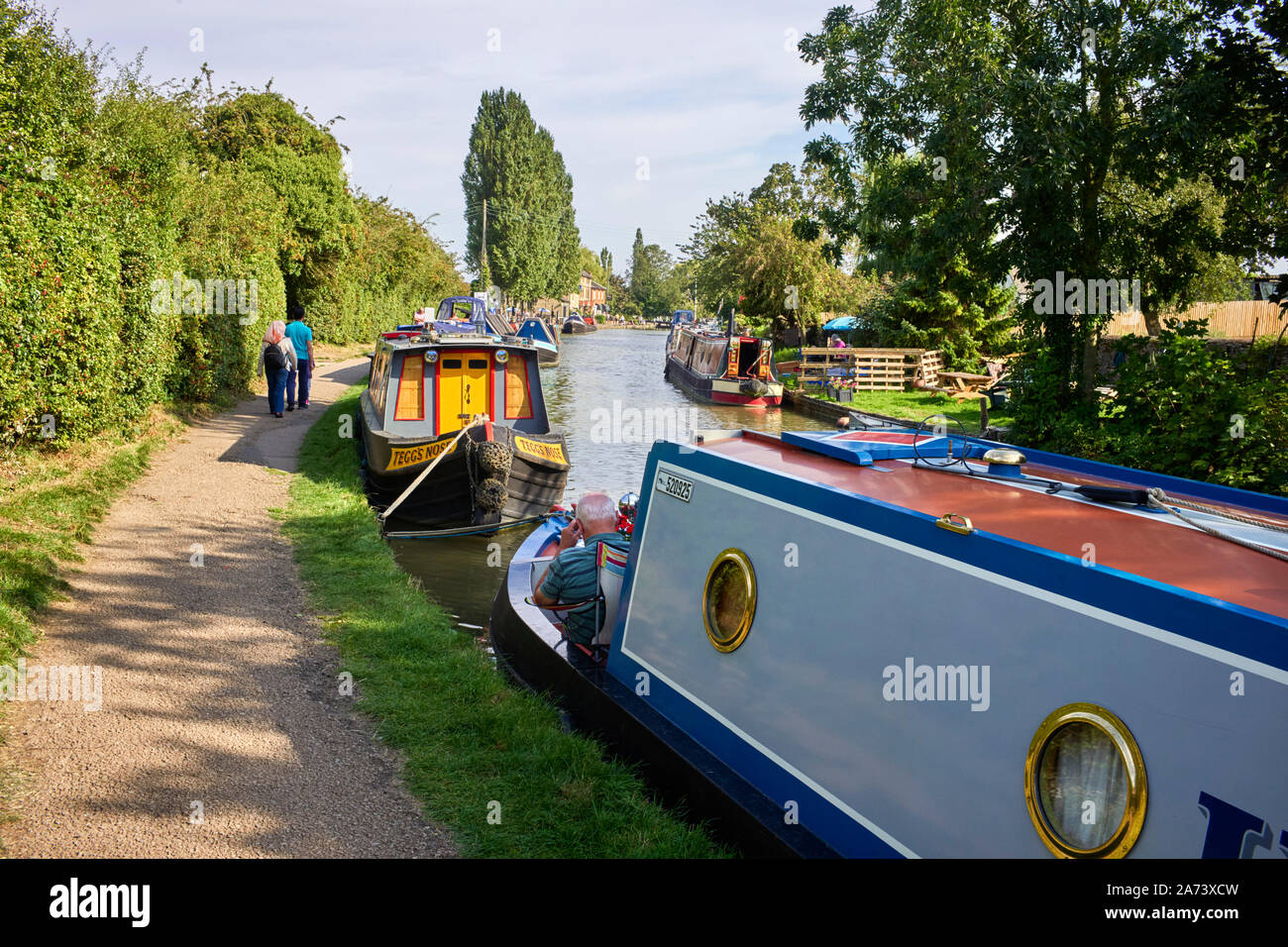 Narrowboats moored along the towpath at Stoke Bruerne on the Grand Union Canal Stock Photo