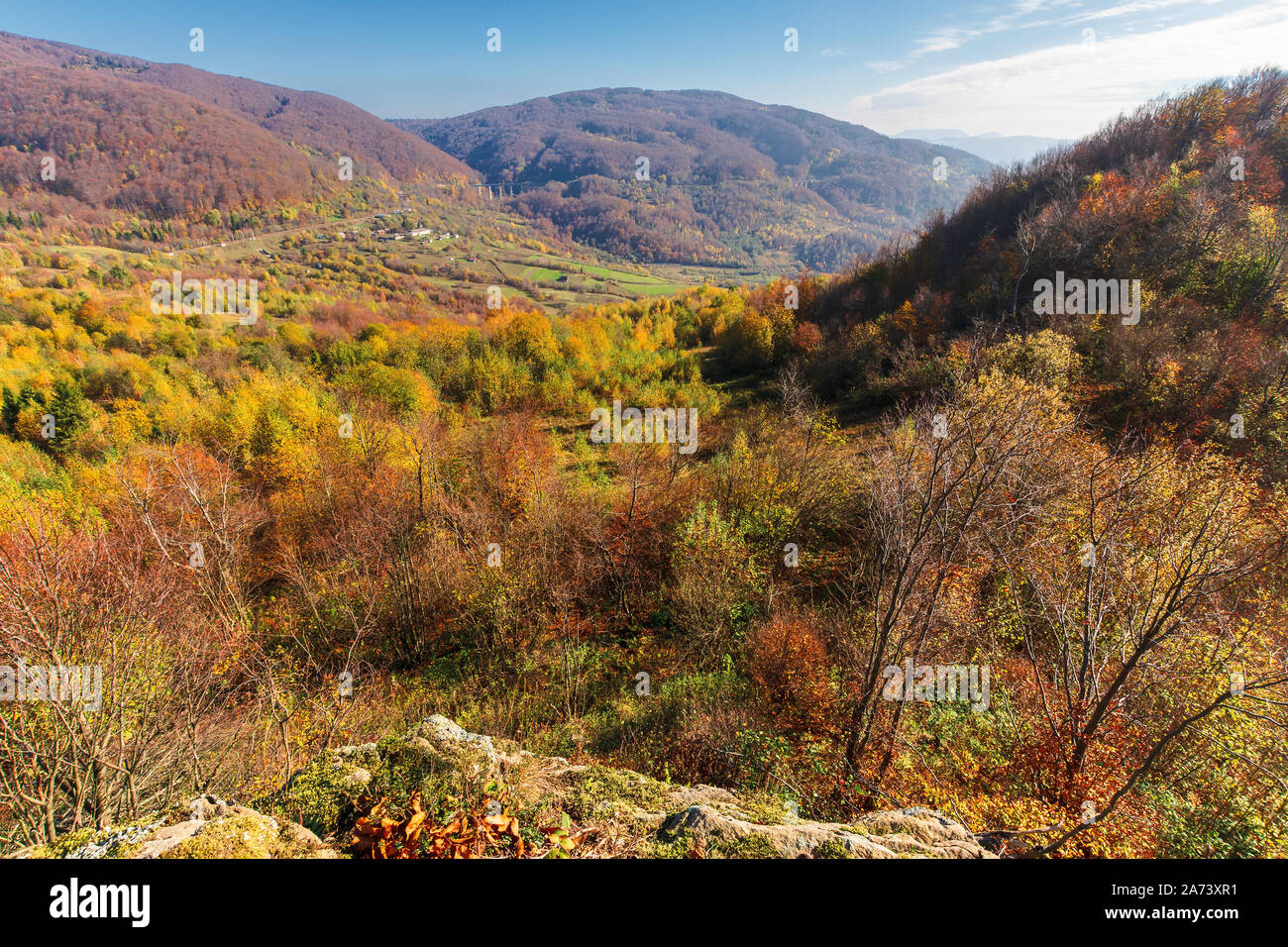 autumn scenery in mountains on a sunny day. view from a high vantage point in to the distant valley. trees in colorful foliage. rail station and viadu Stock Photo