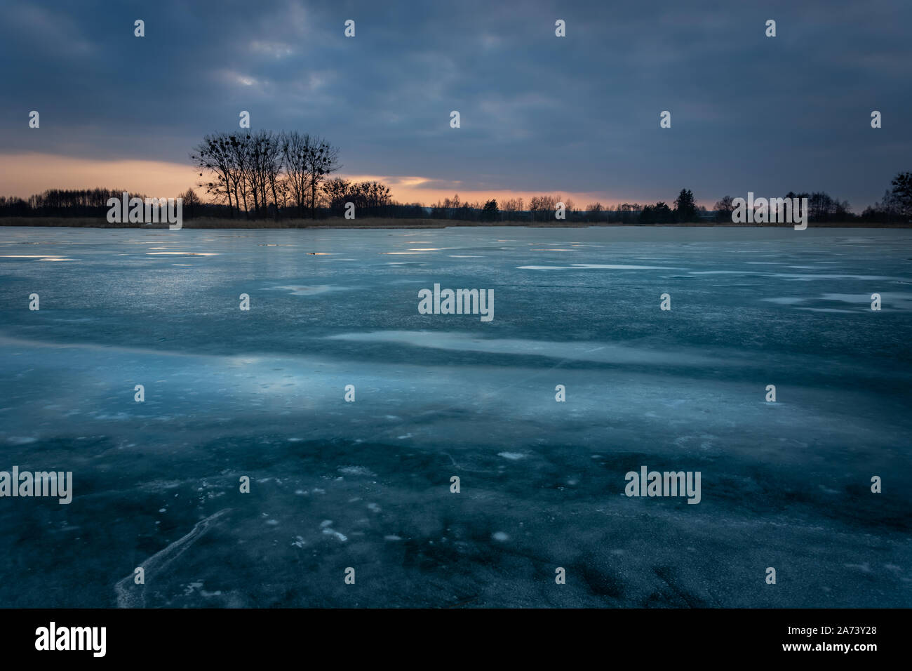 https://c8.alamy.com/comp/2A73Y28/ice-on-a-frozen-lake-trees-on-the-horizon-and-dark-cloud-on-the-sky-evening-view-2A73Y28.jpg