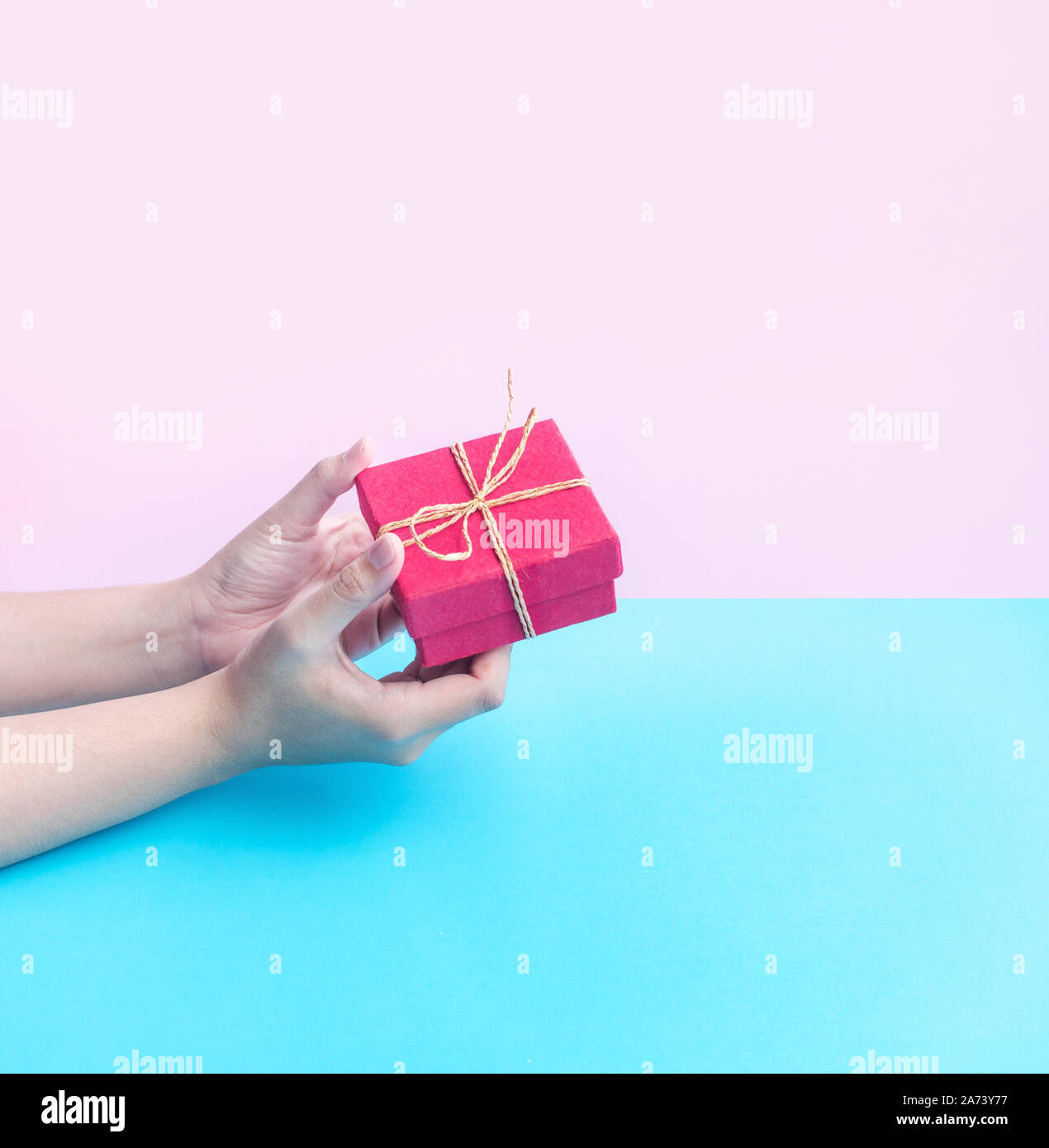 Young woman hand holding colorful gift box on pastel color background.anniversary and christmas background Stock Photo