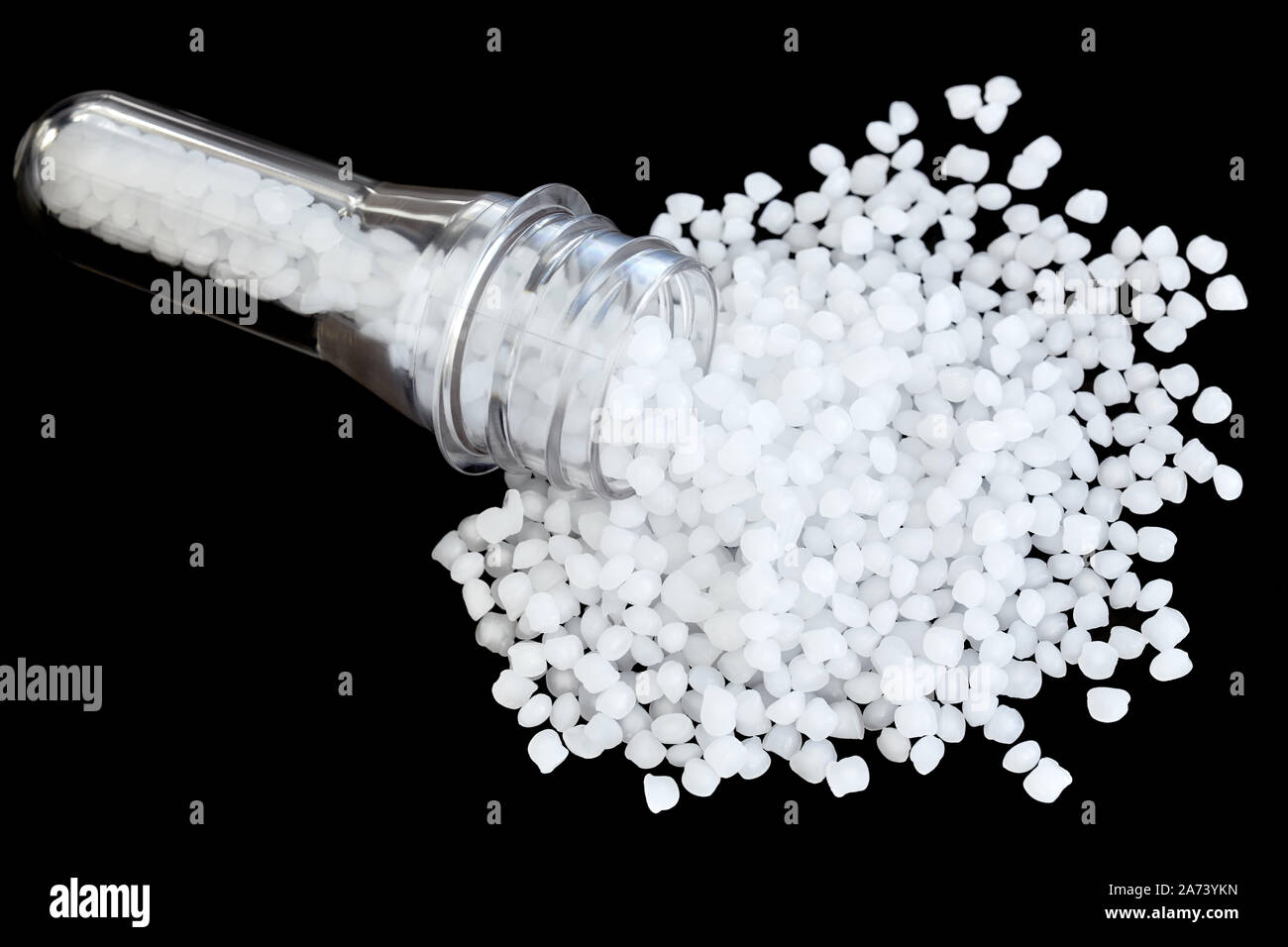 Polypropylene (PP) granules with blow injection molding bottle preform isolated on black background, selective focus. Stock Photo