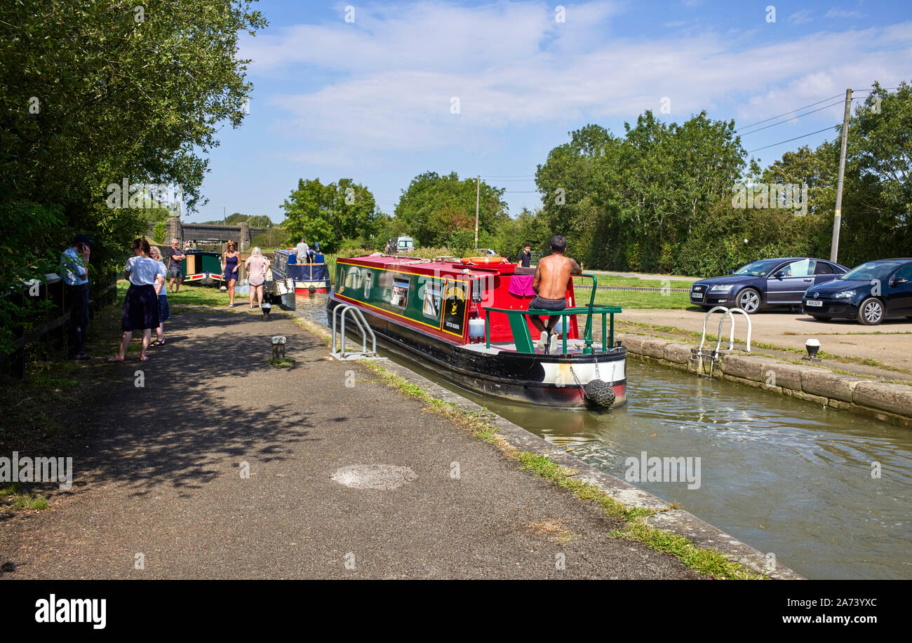Narrowboats leaving on of the Stoke Bruerne locks with a boat waiting to come down on a busy summer weekend Stock Photo