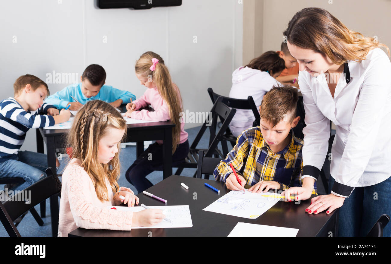Portrait of happy little boys and girls with teacher drawing in ...