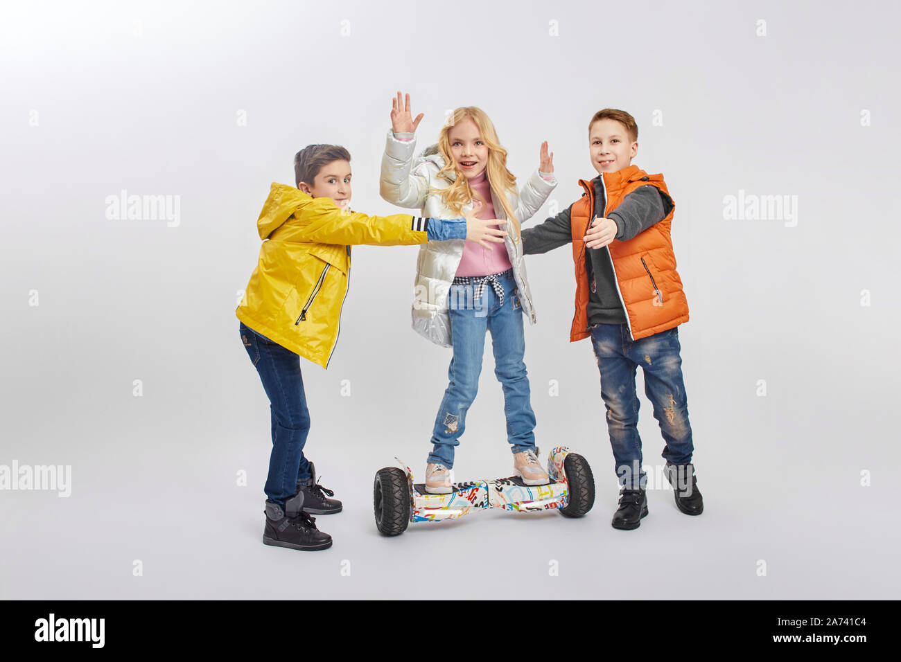 Autumn collection of warm clothes for children. Jackets and down jackets clothing for children. Children have fun and smile, ride a gyro scooter. Russ Stock Photo