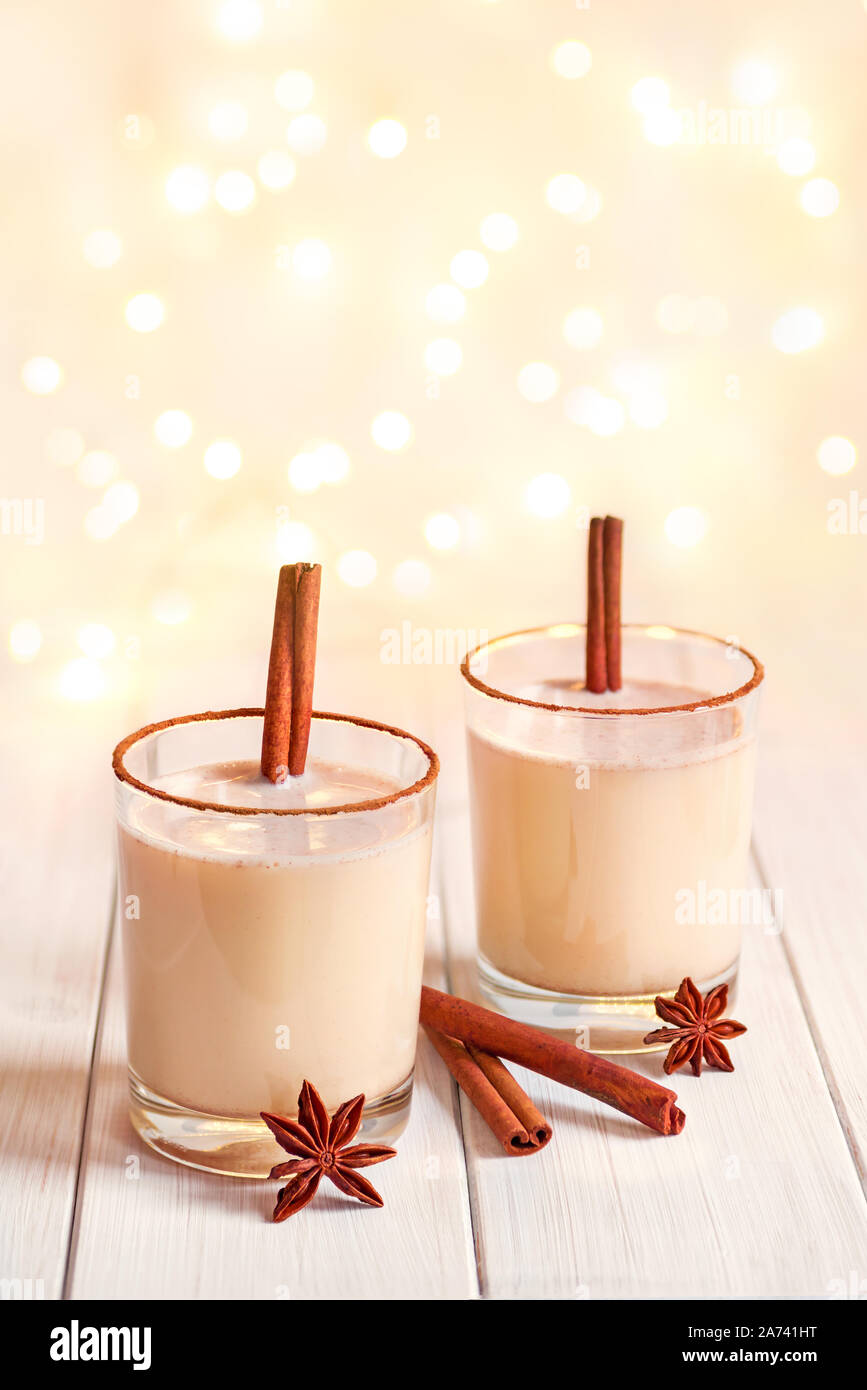 Eggnog in glass cups with a delicate foam, spices and a cinnamon stick ...